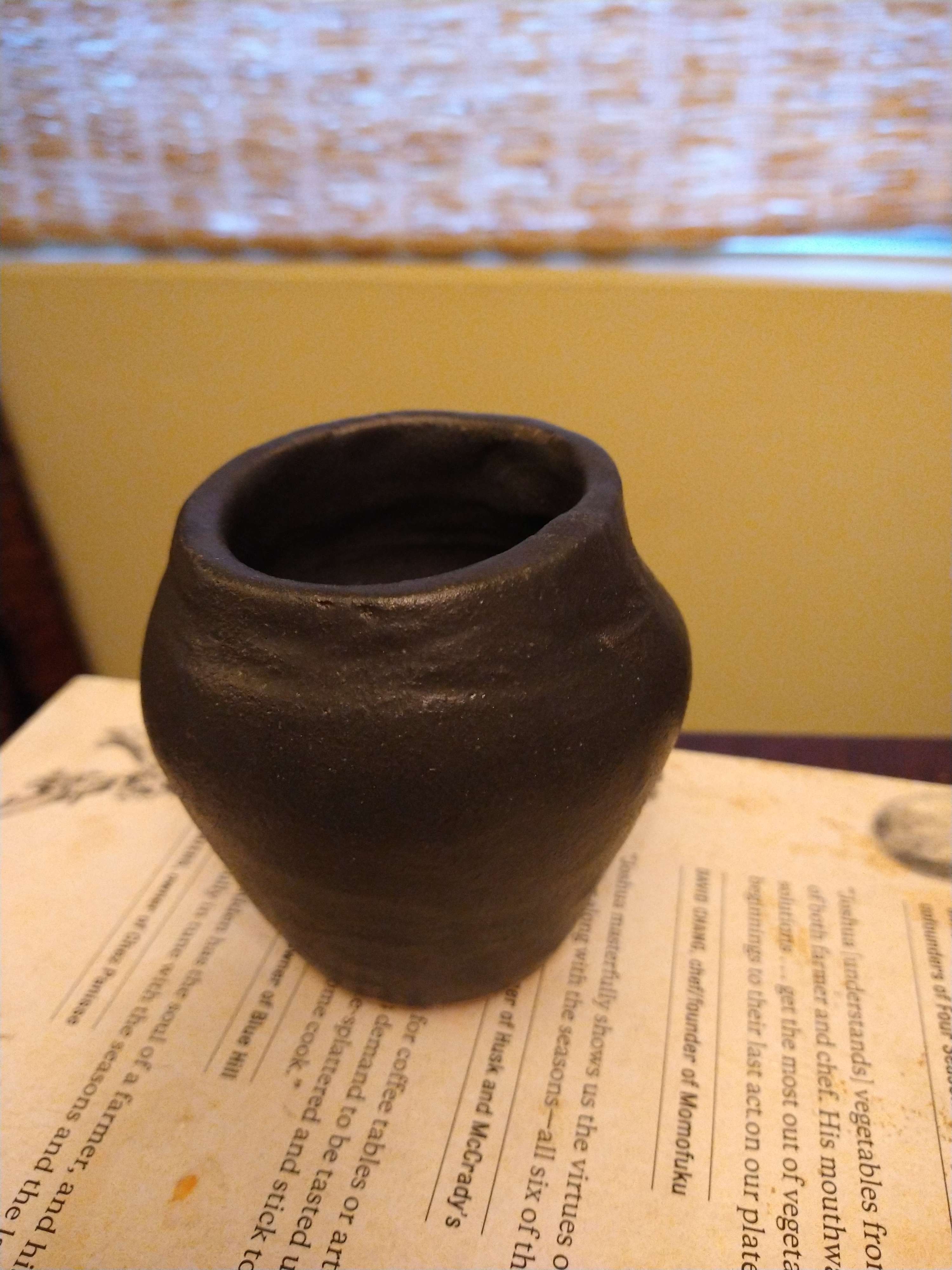 A small black vase with a high shoulder and very narrow base.